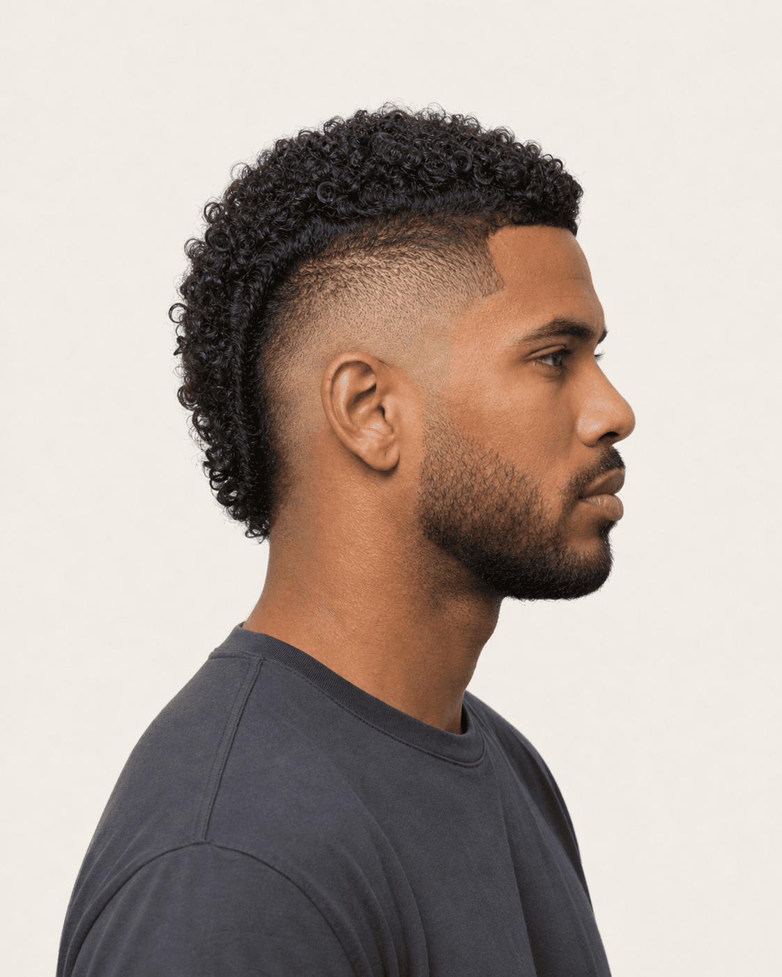 Side profile of a curly mohawk showing the curved burst fade around the ear
